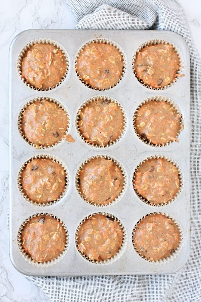 Muffin tins filled with carrot cake muffin batter.