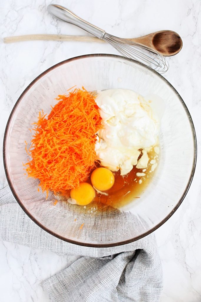 Mixing bowl with wet ingredients: eggs, milk/yogurt, carrots, honey, oil.