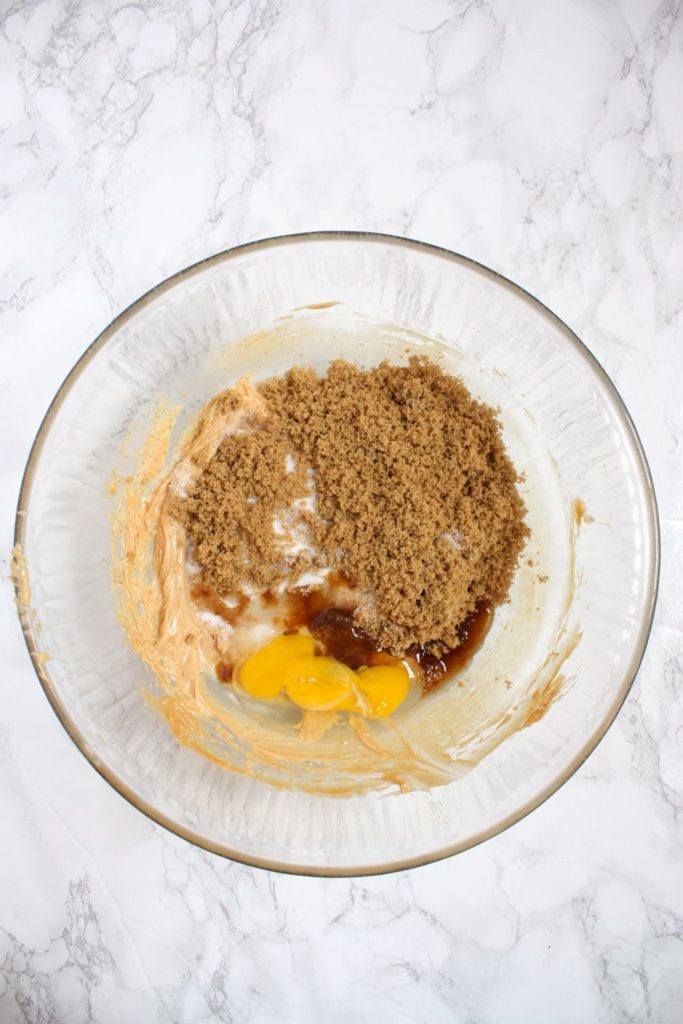 Adding brown sugar, white sugar, and egg to the peanut butter and butter mixture in a mixing bowl.