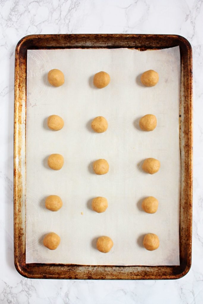 Peanut butter cookie balls on a baking tray before baking.