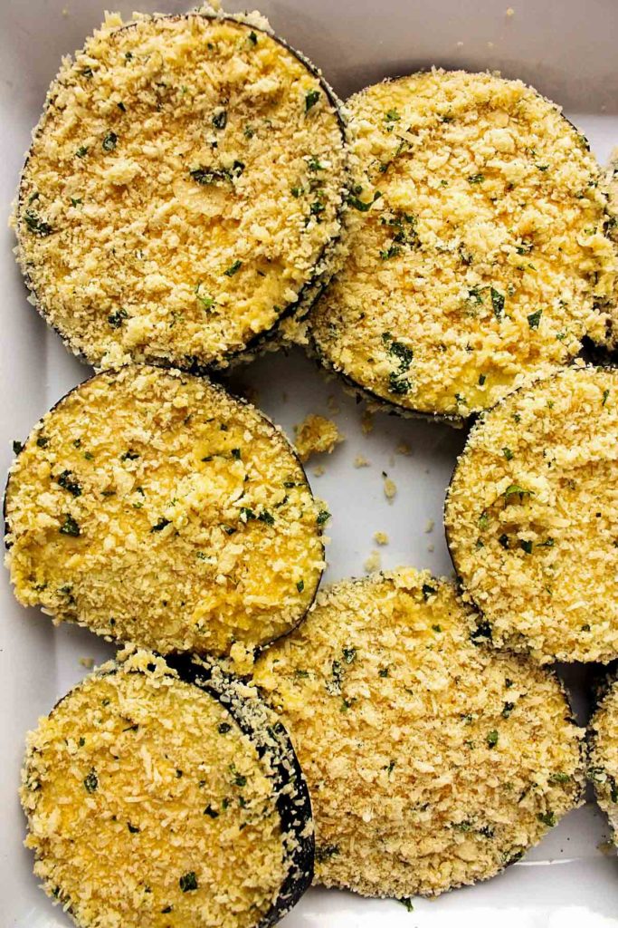 Eggplant rounds coated with panko topping, ready for the oven.