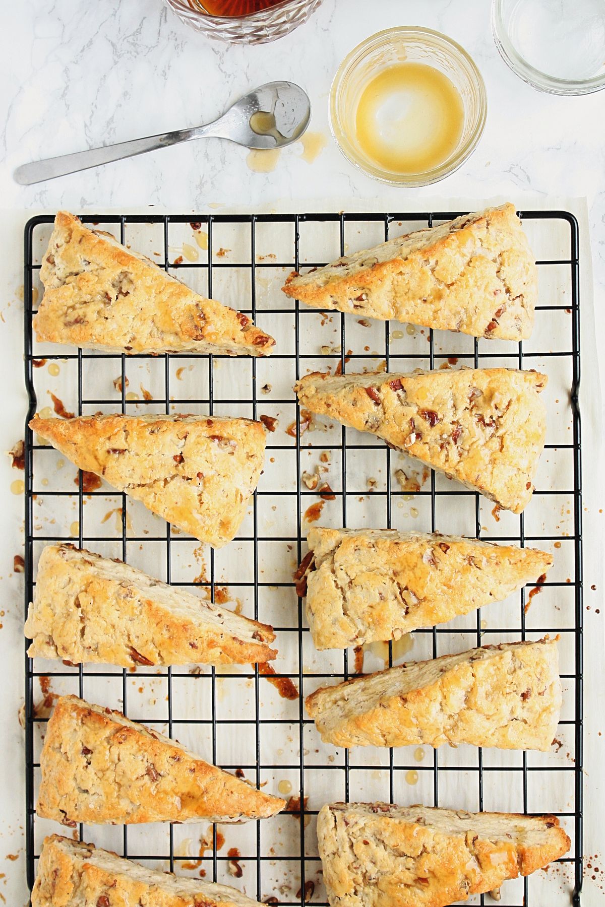 Maple pecan scones with a maple butter glaze on a baking rack.